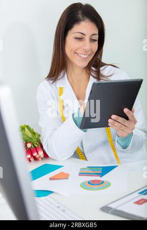 Weibliche Ernährungsberaterin, die am digitalen Tablet arbeitet Stockfoto