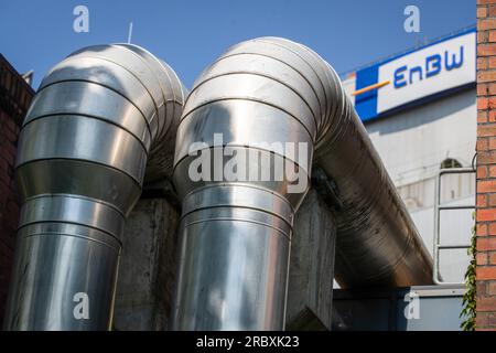 Stuttgart, Deutschland. 11. Juli 2023. Rohrleitungen sind am EnBW-Kraftwerk Stuttgart-Münster vor dem EnBW-Logo zu sehen. Kredit: Christoph Schmidt/dpa/Alamy Live News Stockfoto