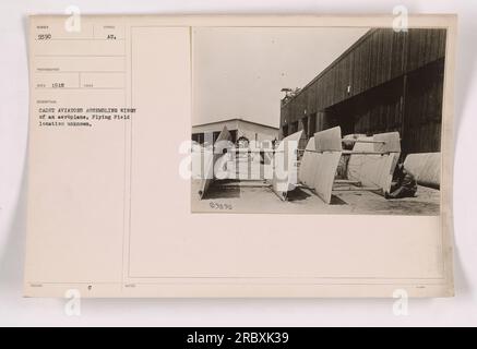 Kadett-Piloten werden gesehen, wie sie die Flügel eines Flugzeugs auf einem unbekannten Flugfeld zusammenbauen. Das Foto, das 1918 vom Fotografen Reco aufgenommen wurde, zeigt die Kadetten, die gemeinsam an der Vorbereitung des Flugzeugs für ihre Trainingsaktivitäten arbeiten. Das Bild trägt die Identifikationsnummer 9390 aus der Sammlung Fotos von amerikanischen Militäraktivitäten während des Ersten Weltkriegs. Stockfoto