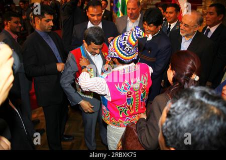 LA PAZ, BOLIVIEN, 19. Juni 2012. Nach seinem Treffen mit dem bolivianischen Präsidenten Evo Morales Ayma im Präsidentenpalast in La Paz überreicht ein bolivianischer indigener Führer in traditioneller Kleidung dem iranischen Präsidenten Mahmoud Ahmadinedschad eine Jacke. Während des Treffens überarbeiteten die Präsidenten frühere bilaterale Abkommen und versprachen, die politischen und wirtschaftlichen Beziehungen weiter auszubauen und im Kampf gegen den Drogenhandel zusammenzuarbeiten. Der Iran unterstützt und finanziert bereits Industrie-, Gesundheits- und Sanitärprojekte in Bolivien. Stockfoto