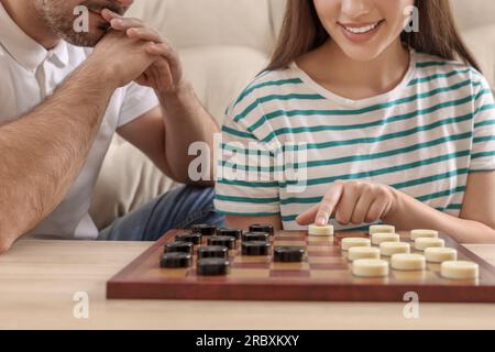 Ein Paar spielt Dame am Tisch im Zimmer, schließt Stockfoto