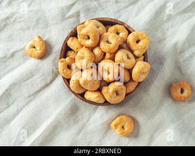 traditioneller italienischer Snack Taralli oder Tarallini in Holzschüssel auf hellem Leinenserviettenhintergrund. Rustikale Aufnahme einer Taralli-Vorspeise mit Kopierraum. Draufsicht oder flach liegend. Stockfoto