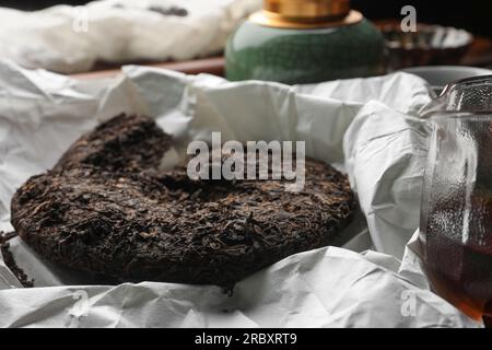 Gebrochener scheibenförmiger pu-erh-Tee auf Pergamentpapier Stockfoto