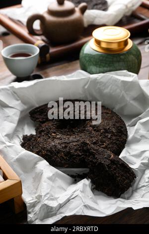 Gebrochener, scheibenförmiger pu-erh-Tee auf dem Tisch Stockfoto