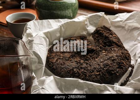 Gebrochener scheibenförmiger pu-erh-Tee auf Pergamentpapier Stockfoto