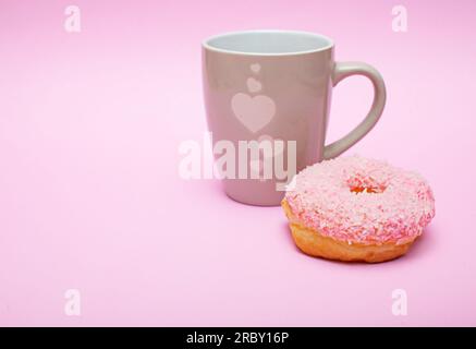 Rosafarbene glasierte Donuts und eine Tasse Kaffee auf rosafarbenem Hintergrund und rosafarbener Hintergrundansicht der Seite Kopierraum, Nahaufnahme, Bäckerei, Café-Menü, Frühstück Stockfoto