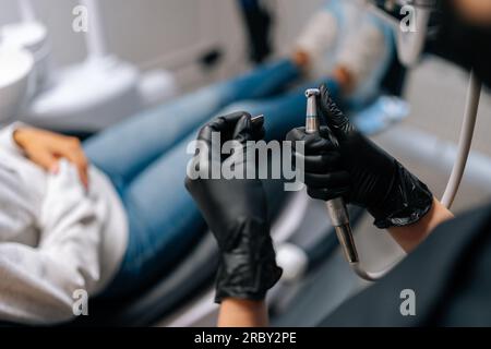 Nahaufnahme der Rückansicht einer nicht erkennbaren Zahnarztfrau in Handschuhen. Bohrer in Werkzeug zur Kariesbehandlung an Zähnen verwandeln. Nahaufnahme des Arzteinsatzes Stockfoto