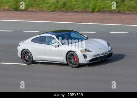 Weißer Porsche Taycan (J1), vollelektrischer Porsche Taycan Turbo S (Modelljahr 2023) in Carrara White Metallic; Fahrt mit hoher Geschwindigkeit auf der Autobahn M6 im Großraum Manchester, Großbritannien Stockfoto