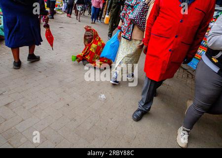 NAIROBI, KENIA, 04. JULI 2023: Ein Straßenbettler sitzt und wartet auf Hilfe von Passanten an den geschäftigen Straßen des Central Business District ( Stockfoto