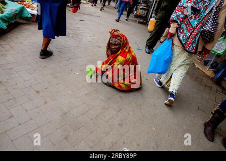 NAIROBI, KENIA, 04. JULI 2023: Ein Straßenbettler sitzt und wartet auf Hilfe von Passanten an den geschäftigen Straßen des Central Business District ( Stockfoto