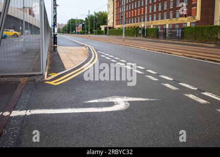 Straßenmarkierungen an einer Kreuzung der Straße und weiß lackierter Richtungspfeil für den Verkehrsfluss Stockfoto