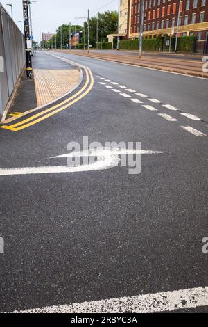 Straßenmarkierungen an einer Kreuzung auf der Straße und weiß lackierter Richtungspfeil für den Verkehr Stockfoto