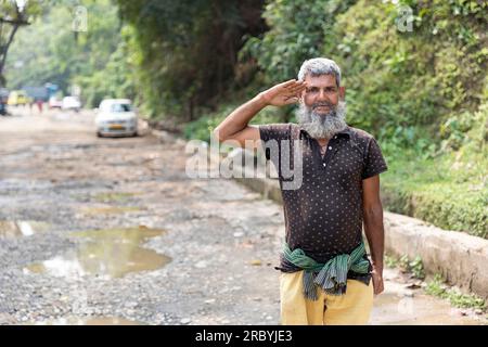 Ein alter oder älterer Mann, der auf der Straße an der Grenze zu Indo Bangladesch, Meghalaya, Indien, grüßt Stockfoto