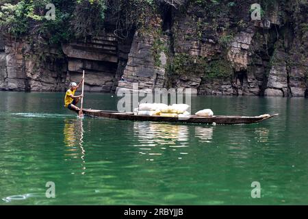 Einheimischer Mann auf einem traditionellen Holzboot, der Waren auf dem Umngot oder Dawki Fluss in Meghalaya, Indien, transportiert Stockfoto