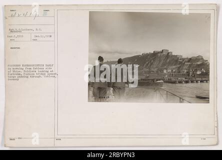 Soldaten beobachten die Festung Ehrenbreitstein von der Koblenzer Seite des Rheins aus am frühen Morgen. Eine Pontonbrücke ist offen, und ein Lastkahn wird durchfahren. Das Foto, aufgenommen von Sergeant H.D. Lothers von der S.C. ist Teil der Sammlung amerikanischer Militäraktivitäten während des Ersten Weltkriegs. Stockfoto