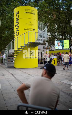 Stuttgart, Deutschland. 11. Juli 2023. Am Schlossplatz in Stuttgart passieren die Menschen einen kleinen Aussichtsturm, der Teil der Informations- und Werbekampagne „The Chänce“ ist. Kredit: Christoph Schmidt/dpa/Alamy Live News Stockfoto