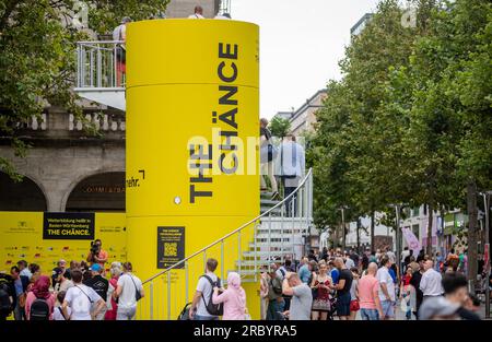 Stuttgart, Deutschland. 11. Juli 2023. Am Schlossplatz in Stuttgart passieren die Menschen einen kleinen Aussichtsturm, der Teil der Informations- und Werbekampagne „The Chänce“ ist. Kredit: Christoph Schmidt/dpa/Alamy Live News Stockfoto