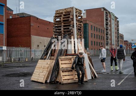 Belfast, Großbritannien. 10. Juli 2023. Jugendliche stehen neben Holzpaletten, die für ein Lagerfeuer bestimmt sind. In der elften Nacht werden Lagerfeuer aus Holzpaletten in protestantischen loyalen Vierteln angezündet. Dieses Jahr wurden die Lagerfeuer aus Sicherheitsgründen reduziert. Die Bonfire Night, die die Schlacht von Boyne feiert, hat eine kontroverse Geschichte und wurde angeprangert, weil sie zu Sektarismus und Hass gegen irische Katholiken und Nationalisten aufstachelt hat. (Foto: Natalia Campos/SOPA Images/Sipa USA) Guthaben: SIPA USA/Alamy Live News Stockfoto