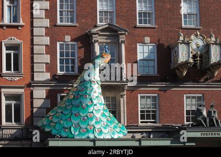 London, Großbritannien - 4. Mai 2023: Britisches Kaufhaus, Fortnum & Mason EST 1707. Eine phänomenale Installation an der Fassade des Gebäudes. Pfauenvogel Stockfoto