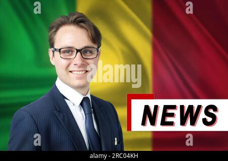 Nachrichtensprecher, erzählt die neuesten Nachrichten, lächelt vor dem Hintergrund der Flagge von Mali. Medien und Propaganda. Stockfoto