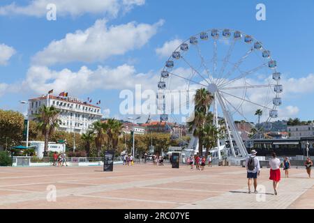 Cannes, Frankreich - 14. August 2018: Touristen gehen an einem sonnigen Sommertag auf der Esplanade Pantiero vor dem Riesenrad spazieren Stockfoto