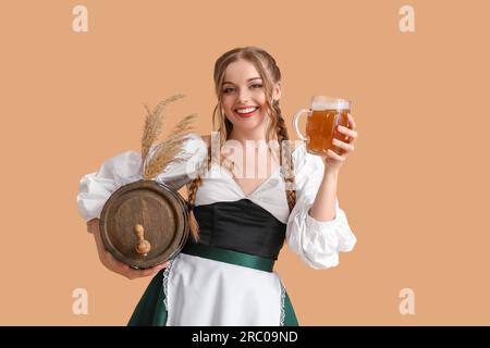 Wunderschöne Oktoberfest-Kellnerin mit Bier und Fass auf beigefarbenem Hintergrund Stockfoto