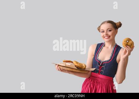 Wunderschöne Oktoberfest-Kellnerin mit Snacks auf hellem Hintergrund Stockfoto