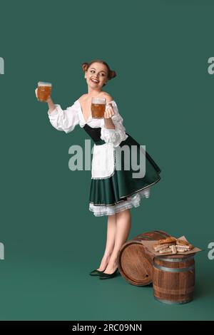 Wunderschöne Oktoberfest-Kellnerin mit Bier und Snacks auf grünem Hintergrund Stockfoto