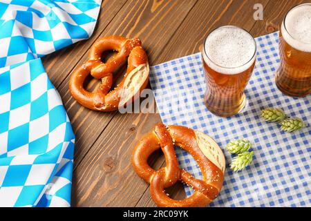 Bayerische Flagge, Tassen mit Bier und Brezeln auf Holzhintergrund Stockfoto