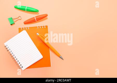 Leeres Notizbuch mit Schreibwaren auf orangefarbenem Hintergrund Stockfoto
