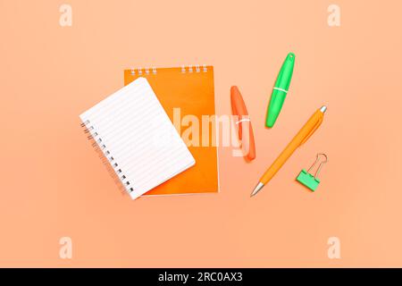 Leeres Notizbuch mit Schreibwaren auf orangefarbenem Hintergrund Stockfoto