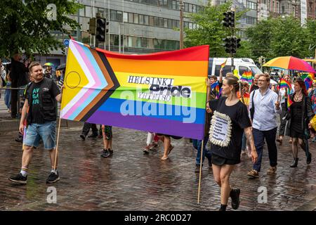 Menschen marschieren und tragen das Helsinki Pride Yhteisö-Banner bei der Helsinki Pride 2023 Parade an einem Regentag in Helsinki, Finnland Stockfoto