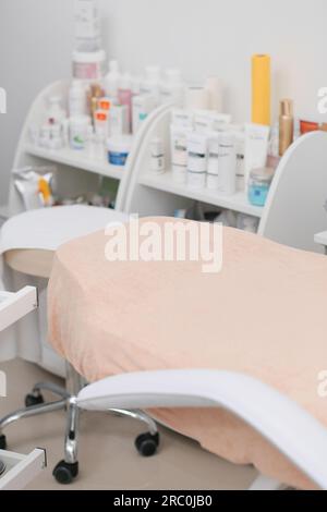 Modernes Kosmetikbüro mit Couch, Kosmetik- und Körperpflegeprodukten. Das Innere des Massageraums, Arztpraxis. Stockfoto