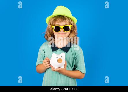 Geld sparen und Sparschwein. Der Junge hat viele hundert Dollar isoliert im Studiohintergrund. Stockfoto