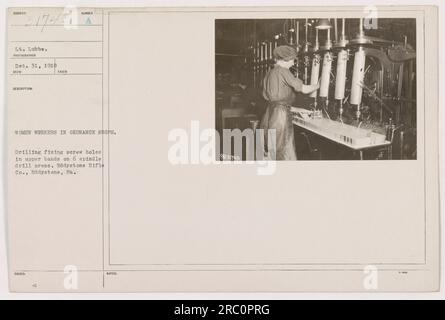 LT. Lubbe beaufsichtigt Arbeiterinnen in einem Ordnance-Laden in Eddystone, Pennsylvania. Das Foto zeigt eine Frau, die mit einer 6-mm-Spindelbohrmaschine an der Eddystone Rifle Co. Schraubenlöcher in oberen Bändern bohrt und befestigt Das Bild wurde am 31. Dezember 1918 aufgenommen, wie in den Notizen des Fotografen angegeben. Stockfoto