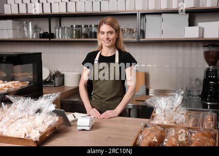 Glücklicher Verkäufer an der Kasse in der Bäckerei Stockfoto
