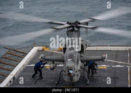 KORALLENSEE, Japan (3. Juli 2023) Seeleute, die auf dem vorwärts ausgesetzten Amphibienschiff USS New Orleans“ (LPD 18) einen AH-1Z Cobra Helikopter auf dem Weg in die Korallensee am 3. Juli zum Cockpit abstellen sollen. New Orleans, Teil der America Amphibious Ready Group, führt derzeit Routinevorgänge im US-7.-Flottenbereich durch. 7. Fleet sind die USA Die größte Flotte der Navy, die mit einer Anzahl von Flotten ausgestattet ist, arbeitet regelmäßig mit Alliierten und Partnern zusammen, um eine freie und offene Region Indopazifik zu erhalten. (USA Navy-Foto von Mass Communication S. Stockfoto