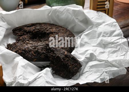 Gebrochener, scheibenförmiger pu-erh-Tee auf einem Holztisch Stockfoto