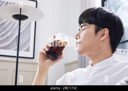 Sommerleben, koreanischer asiatischer junger Mann, der Eiskaffee trinkt Stockfoto