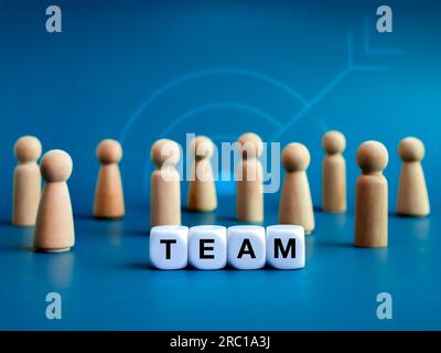 Team, Teamarbeit, Führungs- und Familienbetriebskonzepte. Wörter „TEAM“, Text auf weißen Würfelblöcken und verschiedene hölzerne Figuren, die davor stehen Stockfoto