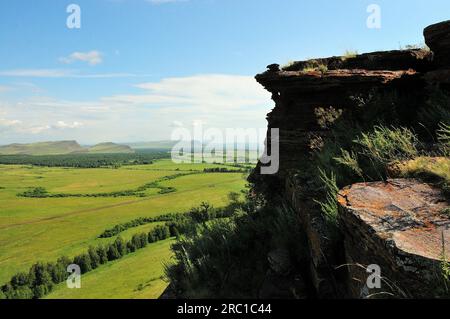Die flache Spitze eines Hügels aus rotem Sandstein mit Blick auf die endlose Sommersteppe. Berghütten, Chakassien, Sibirien, Russland. Stockfoto