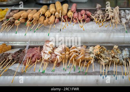 Asiatisches Street Food, Lok Lok, Fleisch- und Fischkuchen auf Spießen. Stockfoto