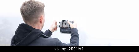 Junger männlicher Fotograf auf nebliger Wiese, der Fotos machte. Stockfoto