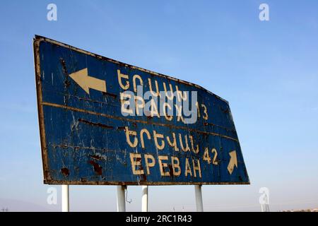 Rostiges Straßenschild in armenisch und kyrillisch 42km vor Eriwan, Armenien Stockfoto