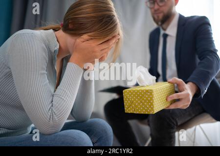 Ein ernsthafter Psychologe hört auf eine weinende Patientin in der Klinik, gekürzt aus der Nähe. Professionelle medizinische Versorgung, Patientenversorgung, Depressionsbehandlung Stockfoto