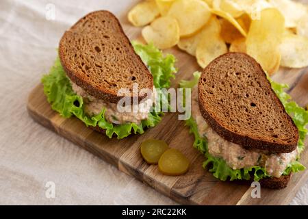 Hausgemachtes Thunfisch-Sandwich mit Salat auf einem Holzbrett, Seitenansicht. Stockfoto