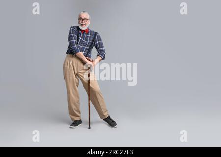 Seniorenmann mit Gehstock auf grauem Hintergrund Stockfoto