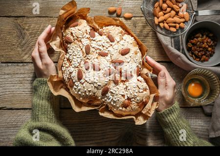 Frau mit köstlichem italienischen Ostertaubenkuchen (traditionell Colomba di Pasqua) am Holztisch, Blick von oben Stockfoto