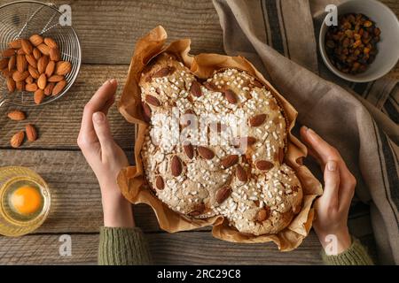 Frau mit köstlichem italienischen Ostertaubenkuchen (traditionell Colomba di Pasqua) am Holztisch, Blick von oben Stockfoto