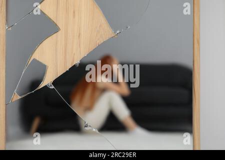 Psychische Probleme. Verschwommenes Spiegelbild einer depressiven Frau im zerbrochenen Spiegel Stockfoto
